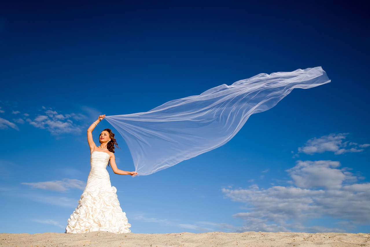 bride with windblown scarf on a tropical beach